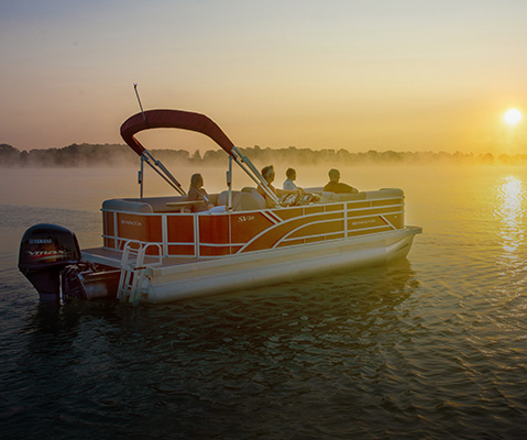 Side view of a parked Bennington Pontoon Boat at sunset. 