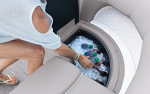 A woman taking out a cold beverage from the integrated storage box of a Bennington.