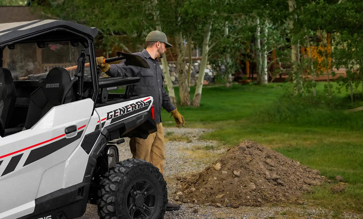 A man scooping up dirt on his Polaris GENERAL 1000