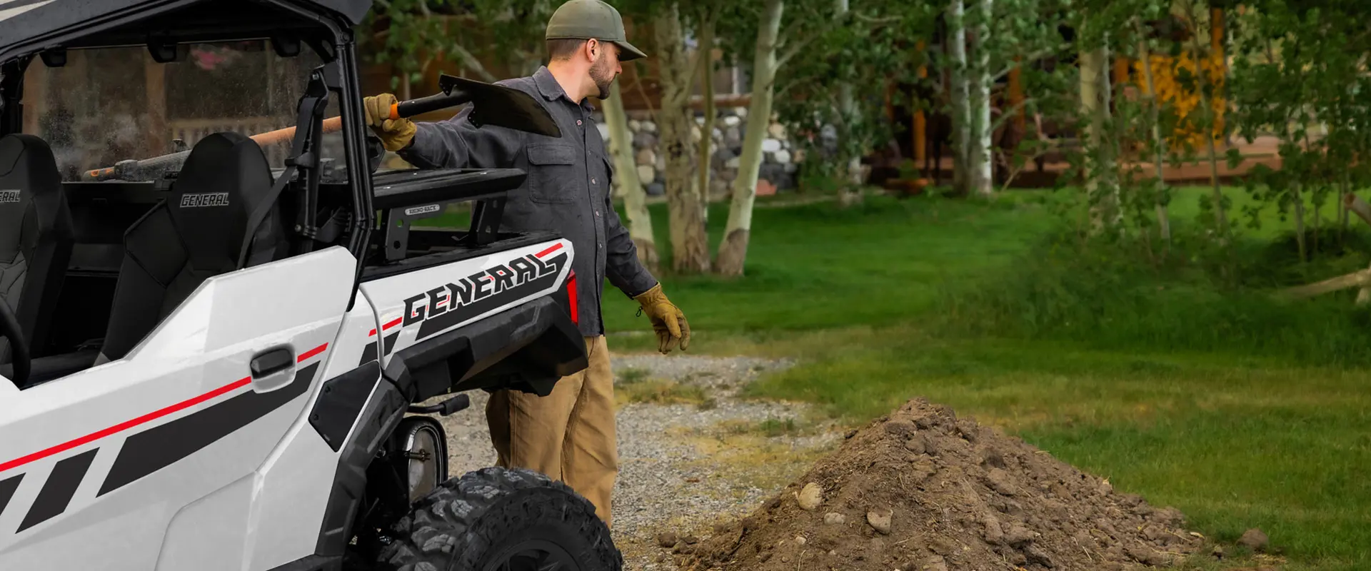 A man scooping up dirt on his Polaris GENERAL 1000
