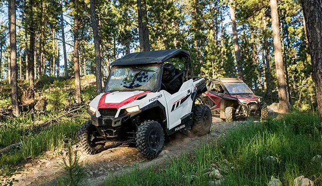 Two Polaris General 1000 in a trail road