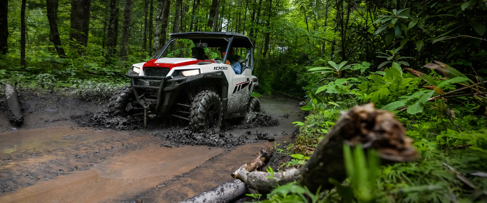 A Polaris GENERAL 1000 riding a muddy road