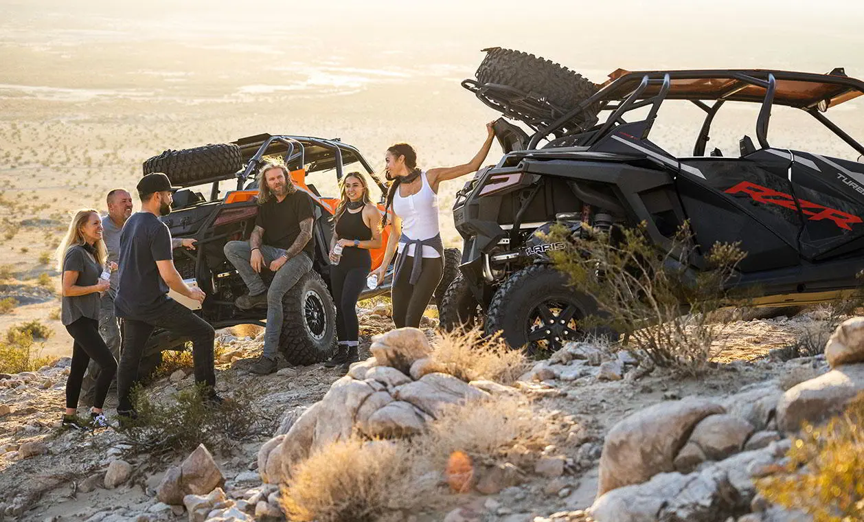Group of people around their RZR TURBO R vehicles