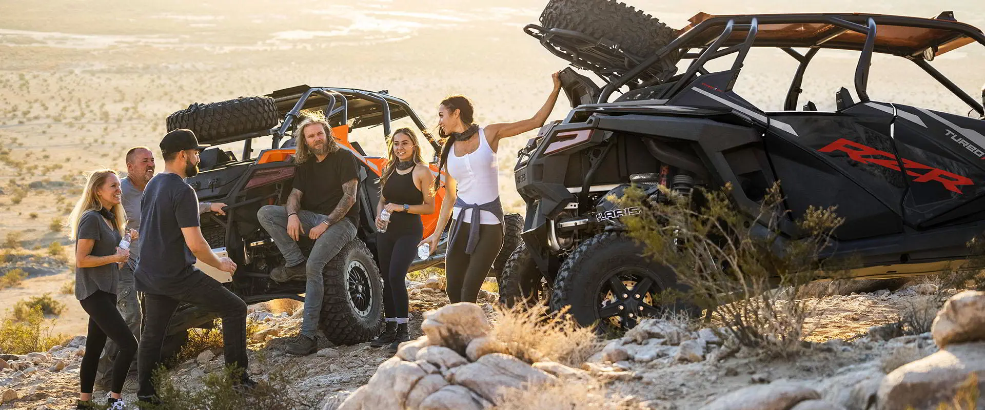 Group of people around their RZR TURBO R vehicles