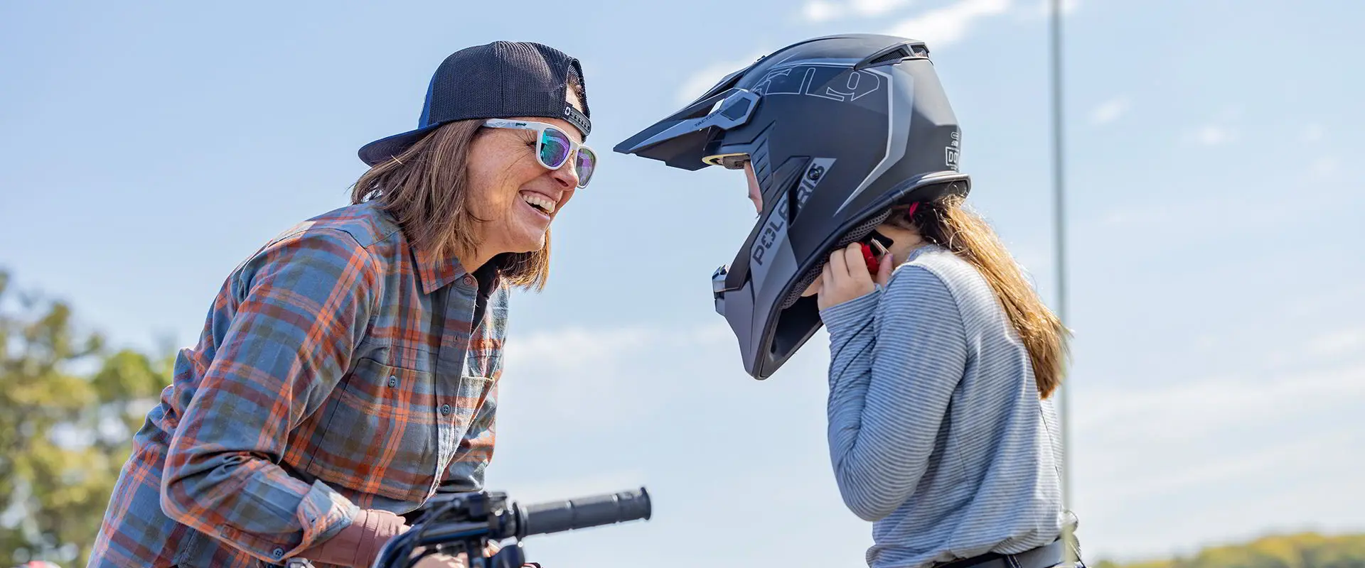 Maman souriant à sa fille après une randonnée dans son VTT pour jeunes Polaris Sportsman 110 2025.