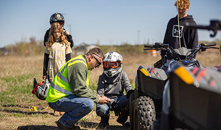 Instructor explaining ATV safety to a child in a helmet at a 4-H program.