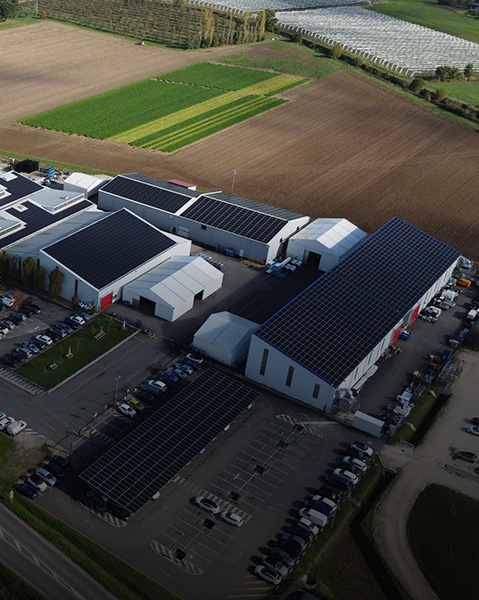 Aerial view of a Polaris facility with multiple industrial buildings topped with solar panels, surrounded by parking lots, farmland, and access roads.