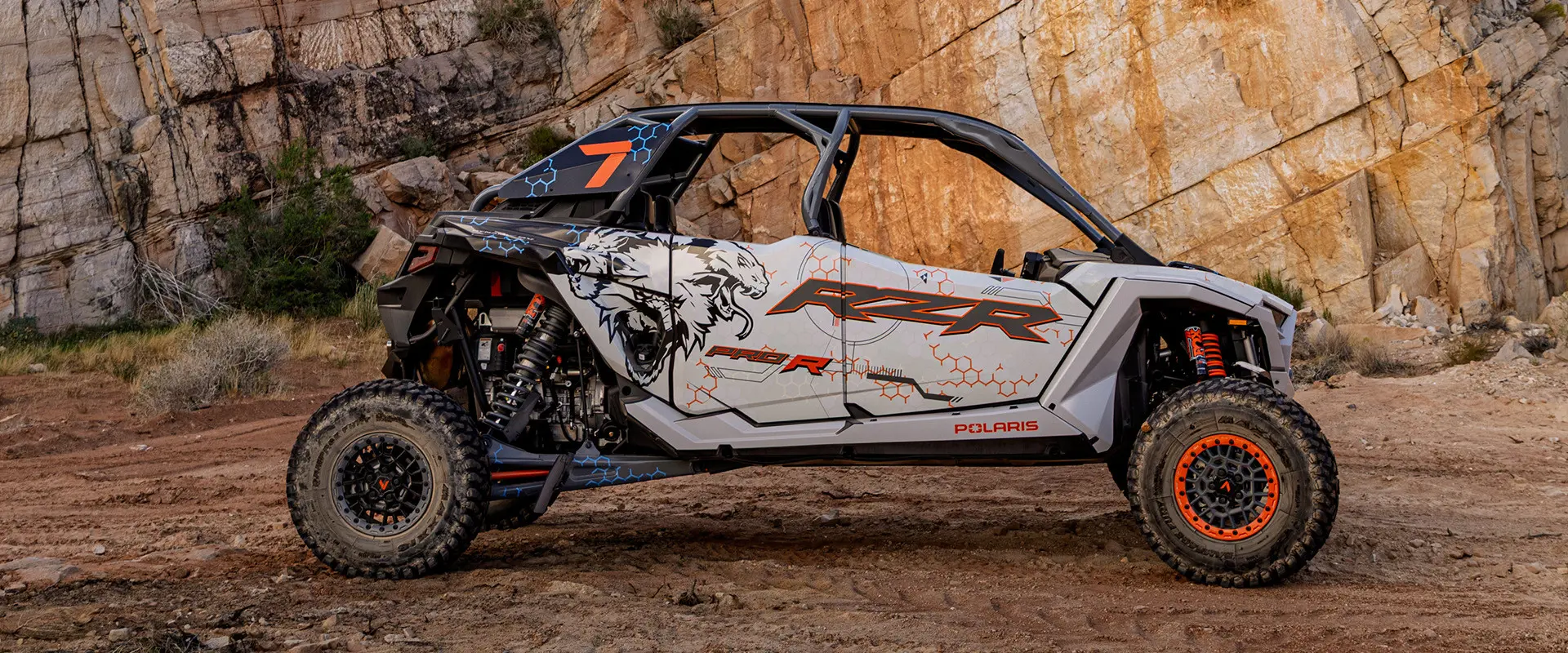 Side profile of a 2025 Polaris RZR Pro R 4 side-by-side throwing sand in the desert.