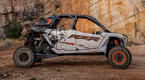 Side profile of a 2025 Polaris RZR Pro R 4 side-by-side throwing sand in the desert.