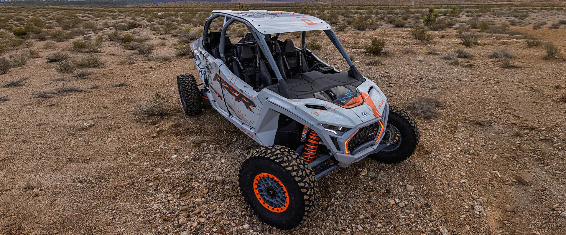 An aerial view of a white and grey Polaris RZR Pro R 4 SxS parked in a sparsely vegetated desert.