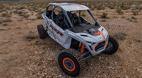 An aerial view of a white and grey Polaris RZR Pro R 4 SxS parked in a sparsely vegetated desert.