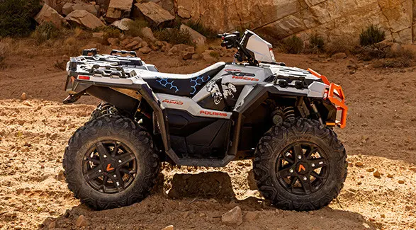 A white and grey Polaris Sportsman XP 1000 ATV is parked on a rocky desert trail.