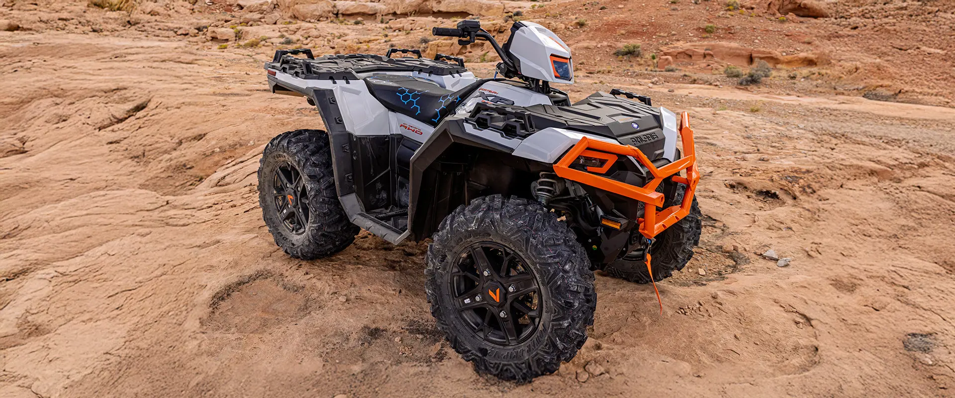 A white and grey Polaris Sportsman XP 1000 ATV is parked on red rocky terrain.