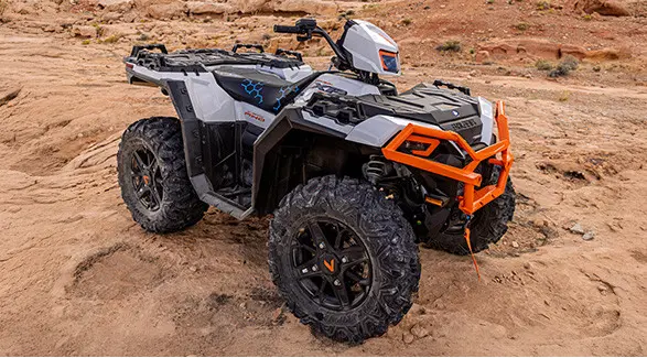 A white and grey Polaris Sportsman XP 1000 ATV is parked on red rocky terrain.