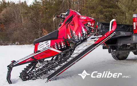 Polaris snowmobile being loaded onto a truck using a Caliber ramp.