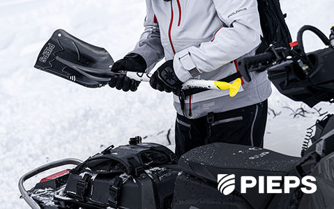 Person assembling a PIEPS avalanche shovel next to a Polaris Snowmobile.