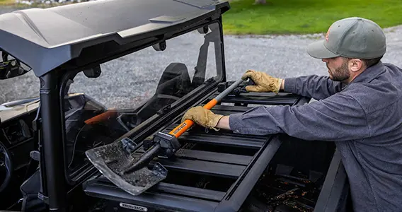 Homme qui place une pelle dans le porte-bagages rhino rack d’un véhicule General