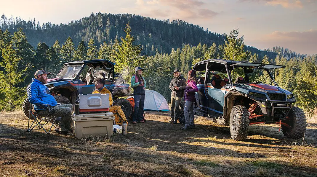 Groupe de conducteurs se détendant sur leur terrain de camping près de leur General XP 1000 édition Trailhead