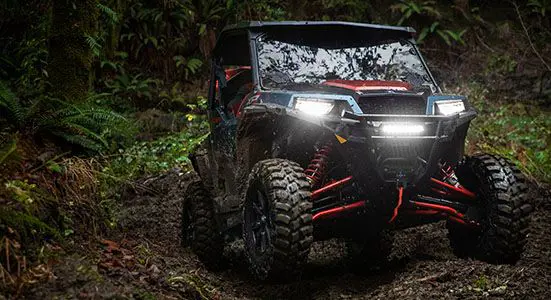 General XP 1000 édition Trailhead avec lumières allumées sur un sentier forestier