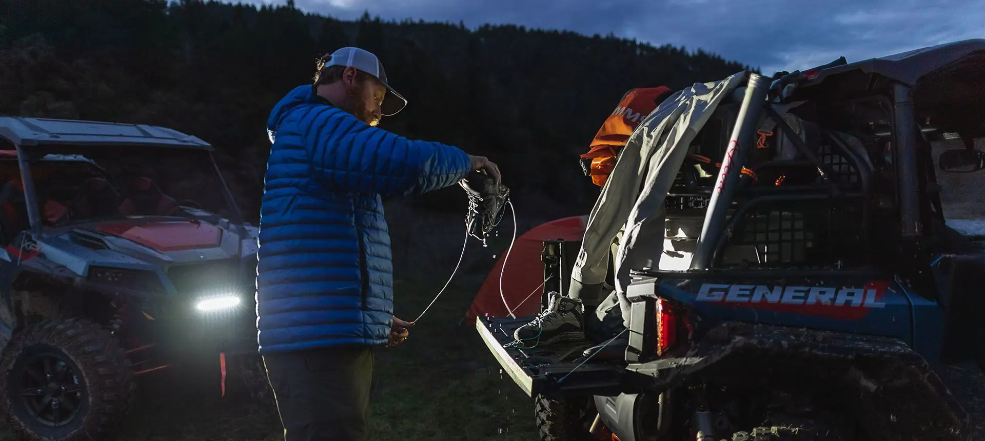Homme déchargeant des bottes de randonnée du coffre de son General XP 1000 édition Trailhead