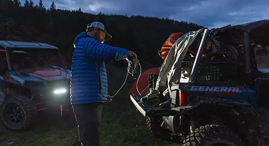 Homme déchargeant des bottes de randonnée du coffre de son General XP 1000 édition Trailhead