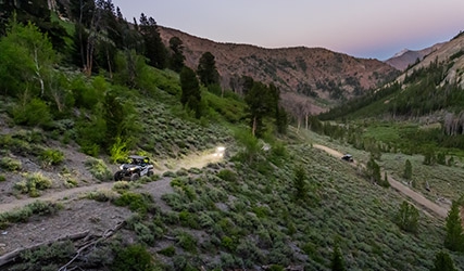 GENERAL XP 1000s cruising on a trail with lights on