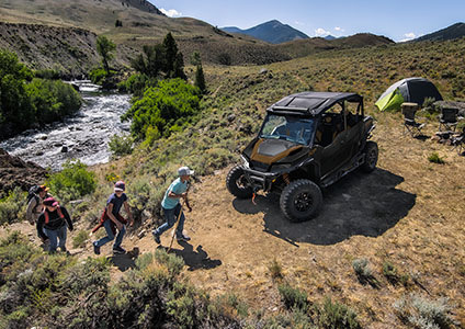 4 hikers walking to their Polaris GENERAL 4 1000 with a windshield