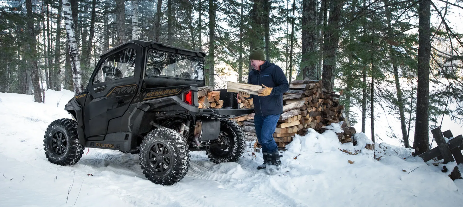 man dumping out a load of wood from the cargo box on his general xp 1000 side by side