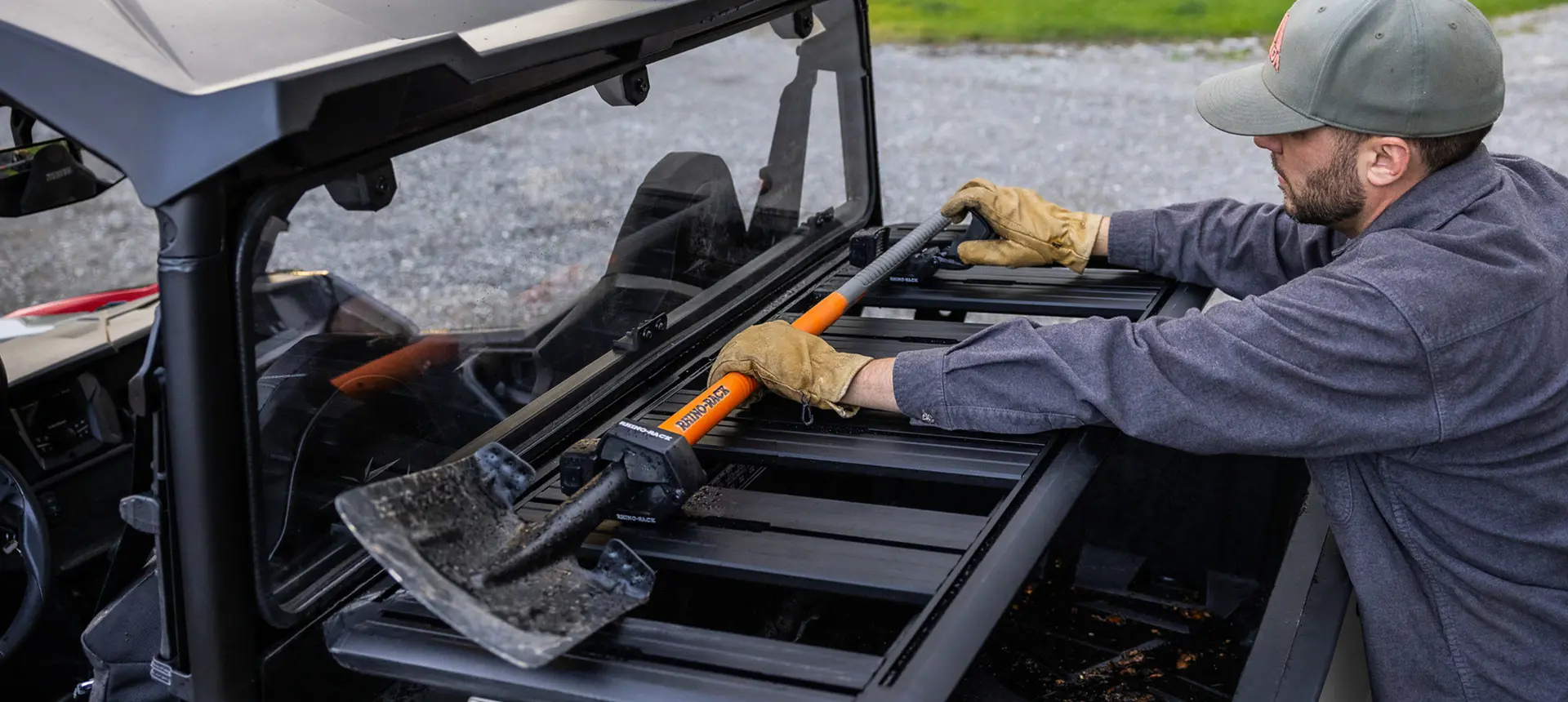 man loading a shovel onto the cargo box on his general xp 1000 side by side