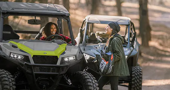 couple unloading their general xp 1000 side by side near a forest trail