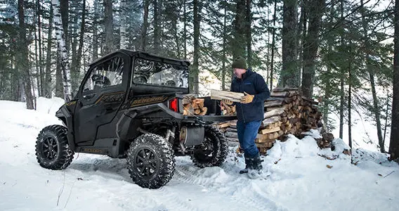 man dumping out a load of wood from the cargo box on his general xp 1000 side by side