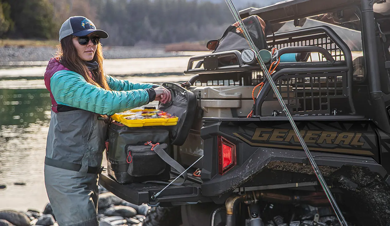 woman getting tackle from the cargo box of her general xp 1000 side by side