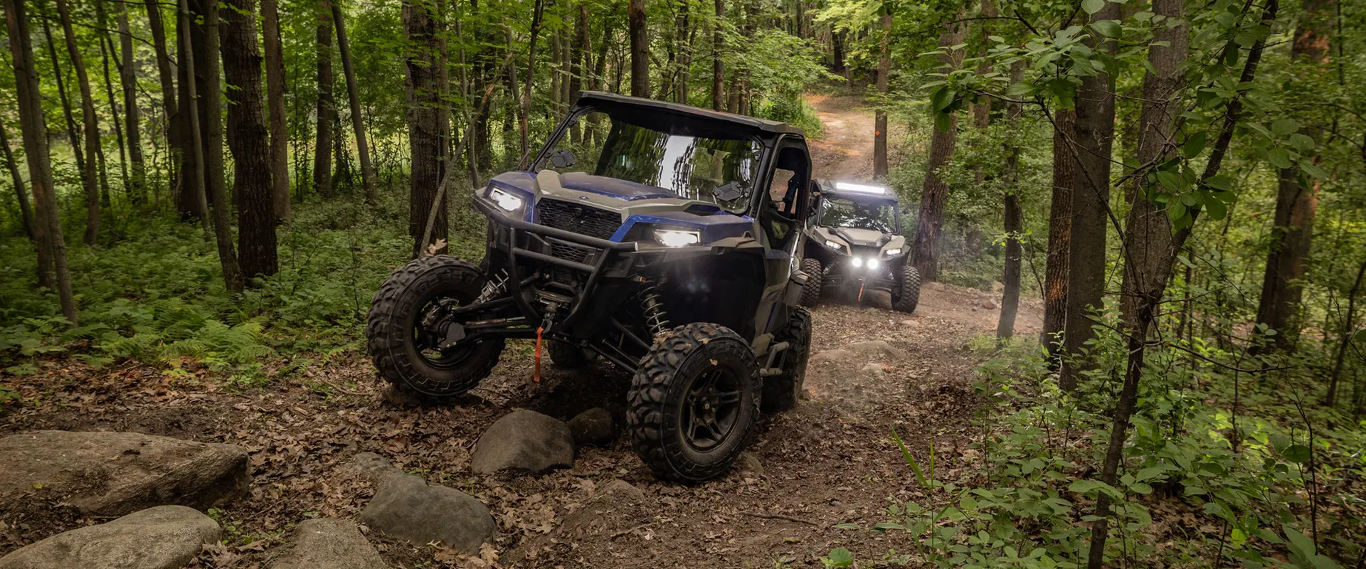 2 general xp 1000 side by sides climbing up a rocky trail
