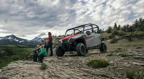 A family of 4 overlooking a valley after a riveting ride in their 2025 Polaris GENERAL 1000 Sport side-by-side.