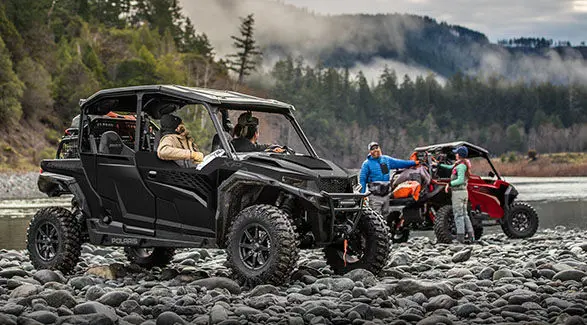 Two riders in a 2025 Polaris GENERAL XP 4 1000 side-by-side talking to 2 other people near their 2025 Polaris GENERAL XP 1000.