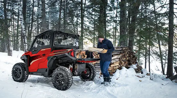 Man loading firewood into the cargo box of his 2025 Polaris GENERAL XP 1000 side-by-side.