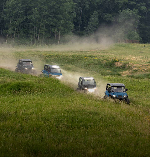 Four 2026 Polaris GENERAL XP 1000 and GENERAL XP 4 1000 SxS UTVs driving through a field.