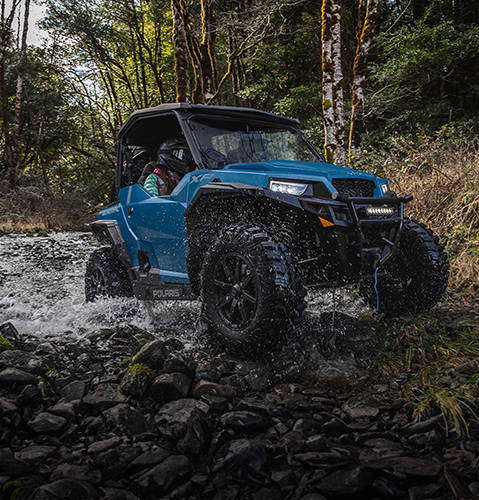 A 2026 Polaris GENERAL XP 1000 SxS UTV powering through a ravine showcasing its trail-capable power for near limitless exploration.