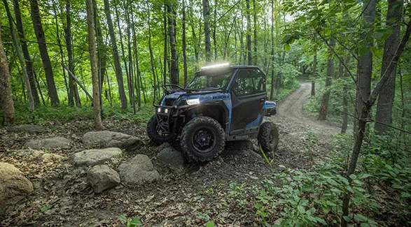 A 2026 Polaris GENERAL crossover side-by-side in the Zenith Blue colorway traversing rocky terrain.
