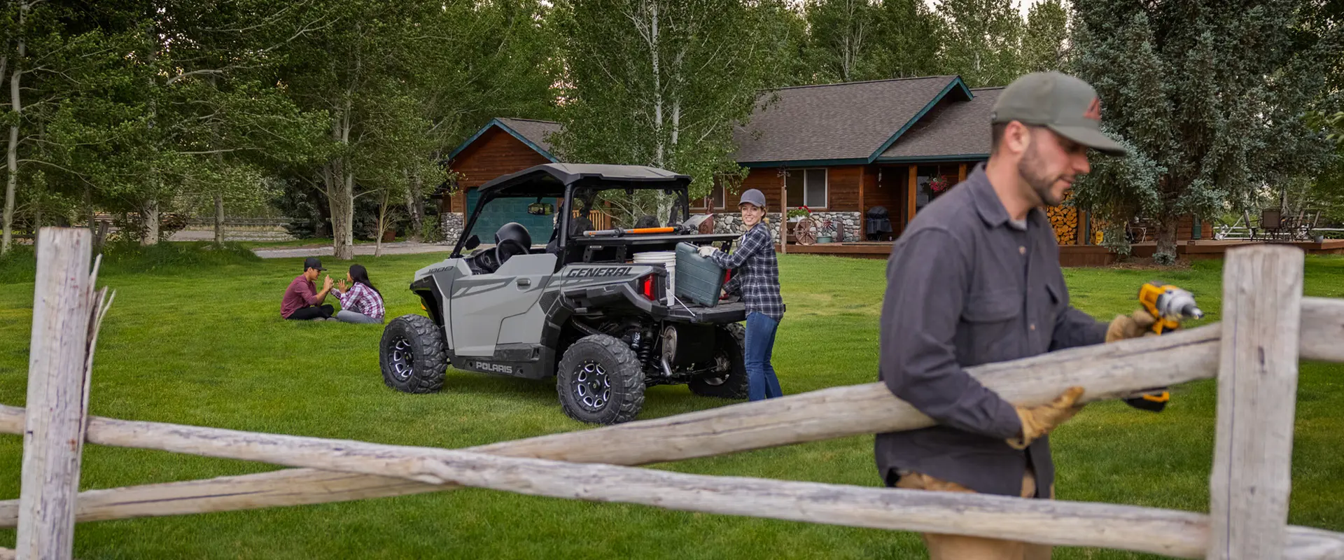 A couple using the cargo box on a 2026 Polaris GENERAL crossover side-by-side to help them install fence.
