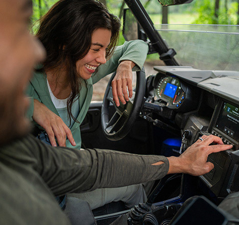 A couple adjusting the off-road optimized Rockford Fosgate audio settings on their RIDE COMMAND touch screen inside of their 2026 Polaris GENERAL XP 1000 SxS.
