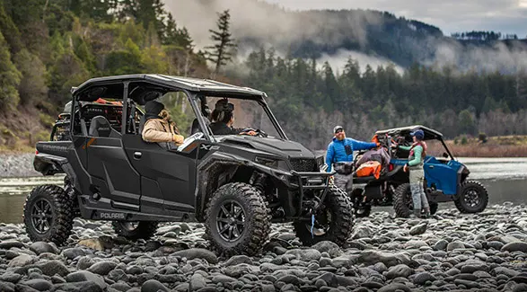 2 people in a 2026 Polaris GENERAL XP 4 1000 crossover side-by-side chatting with 2 other people near their 2026 Polaris GENERAL XP 1000.