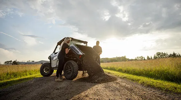 A couple dumping gravel out of the cargo box of their 2026 Polaris GENERAL XP 1000 crossover side-by-side.