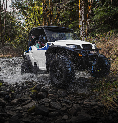 A Polaris GENERAL XP 1000 crossover side-by-side UTV crossing through a ravine and climbing over rocky terrain.