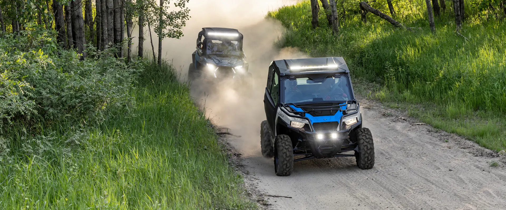 2 2027 Polaris GENERAL 1000 side-by-sides cruising down a dusty trail.