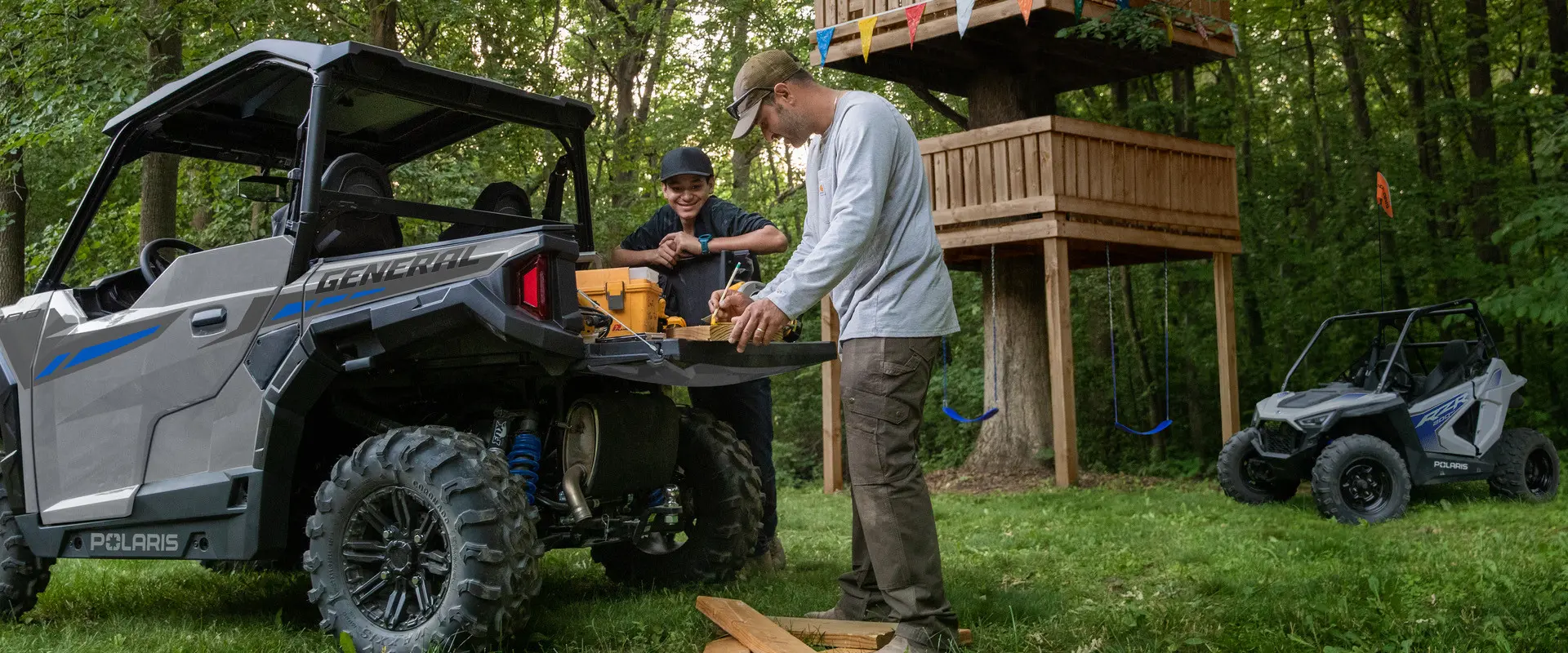 A father and son marking wood on the tail gate of their 2027 Polaris GENERAL 1000 side-by-side.
