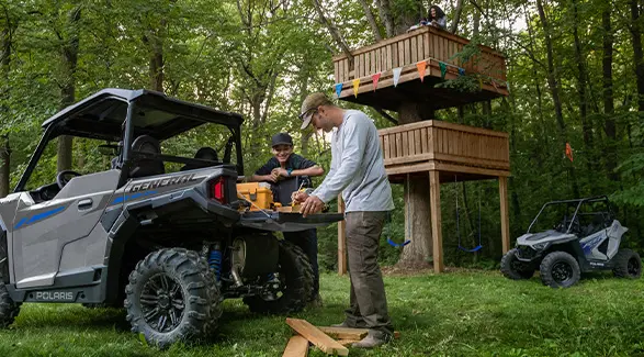 A father and son marking wood on the tail gate of their 2027 Polaris GENERAL 1000 side-by-side.