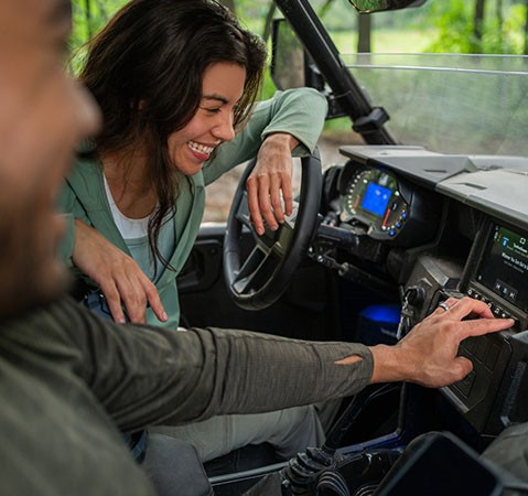 2 people smiling while listening to music through the Rockford Fosgate speakers in a 2027 Polaris GENERAL XP .1000 side by side.