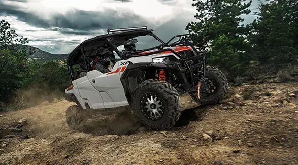 4 riders in a 2027 Polaris GENERAL XP 4 1000 side-by-side climbing over rocky terrain with ease.