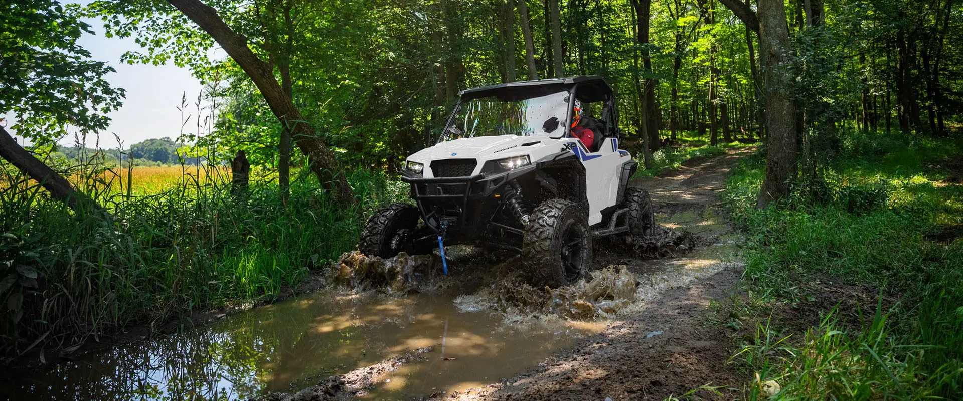A rider in a 2027 Polaris GENERAL XP 1000 side-by-side driving through the mud.